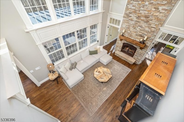 living room with a high ceiling, baseboards, wood finished floors, and a stone fireplace