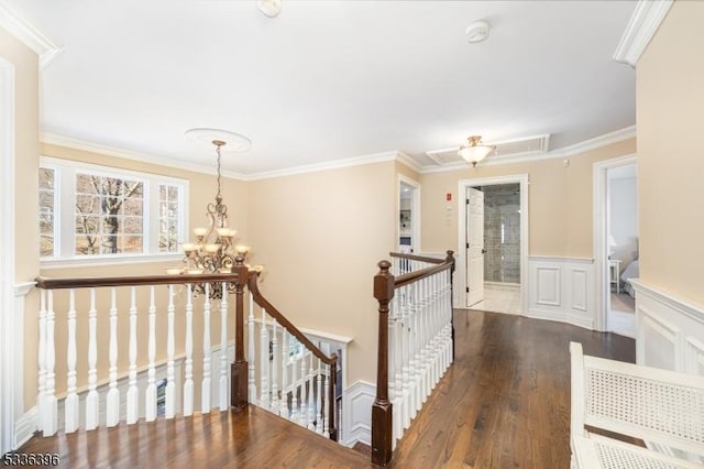 hallway with crown molding, wainscoting, an upstairs landing, wood finished floors, and a chandelier