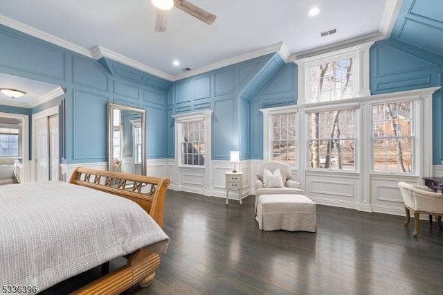 bedroom featuring multiple windows, a decorative wall, and crown molding