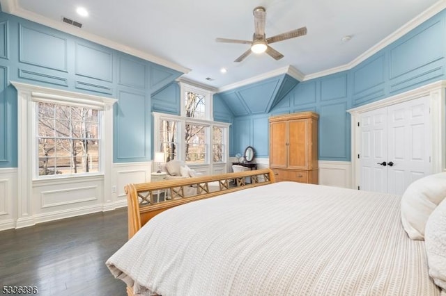 bedroom with visible vents, a decorative wall, dark wood-type flooring, ornamental molding, and vaulted ceiling