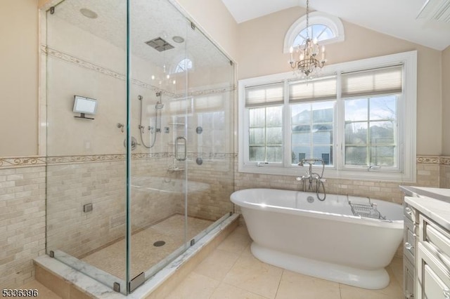 bathroom featuring a notable chandelier, a soaking tub, a stall shower, vaulted ceiling, and vanity