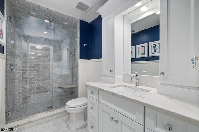 bathroom featuring a stall shower, visible vents, wainscoting, toilet, and vanity