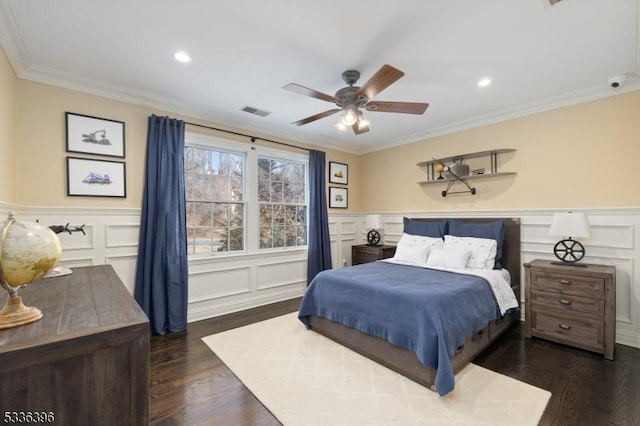 bedroom featuring visible vents, ornamental molding, a decorative wall, and dark wood-style flooring