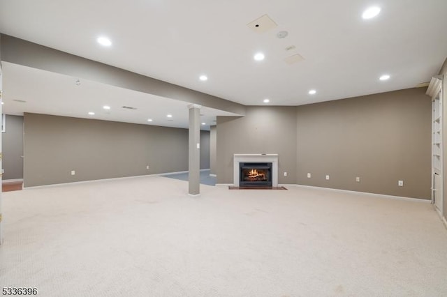 finished basement featuring recessed lighting, a warm lit fireplace, light colored carpet, and baseboards