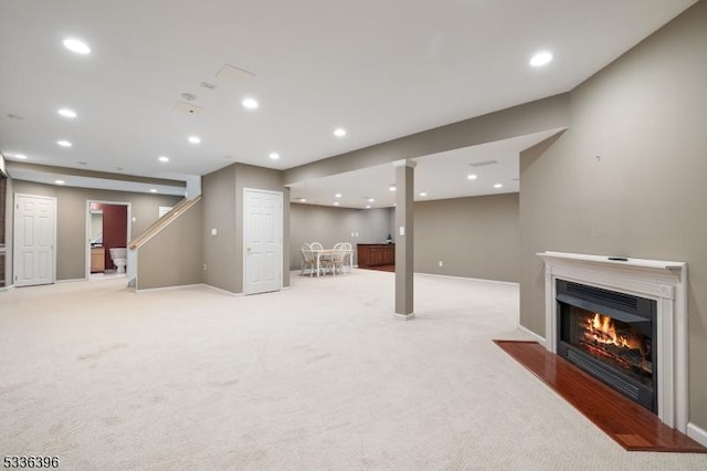 finished basement with baseboards, light carpet, a fireplace with flush hearth, and recessed lighting