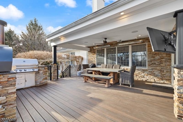 deck featuring an outdoor kitchen, outdoor dining area, a ceiling fan, and area for grilling