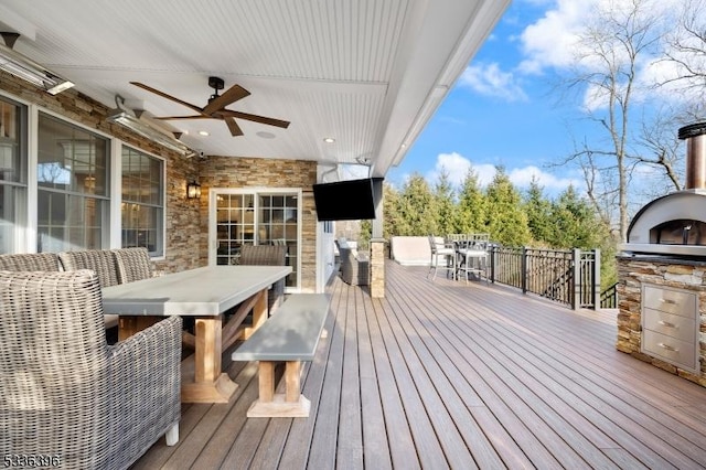 wooden deck featuring a ceiling fan, outdoor dining area, and exterior kitchen