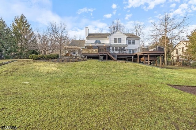 rear view of property with a deck, a lawn, and a chimney