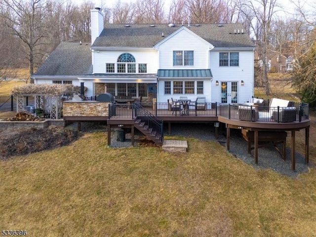 rear view of property featuring french doors, a lawn, a chimney, and a wooden deck