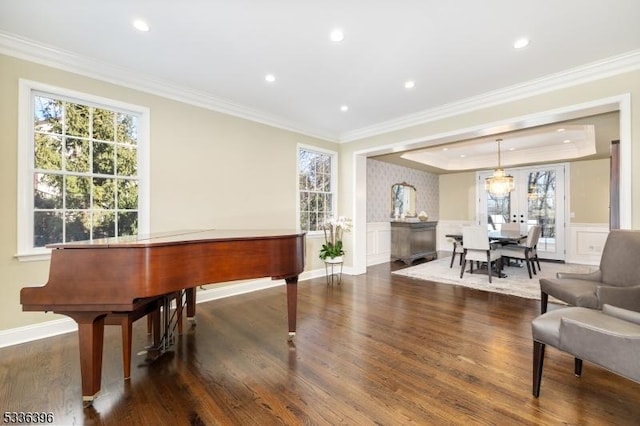 sitting room with a tray ceiling, a wainscoted wall, crown molding, and wood finished floors