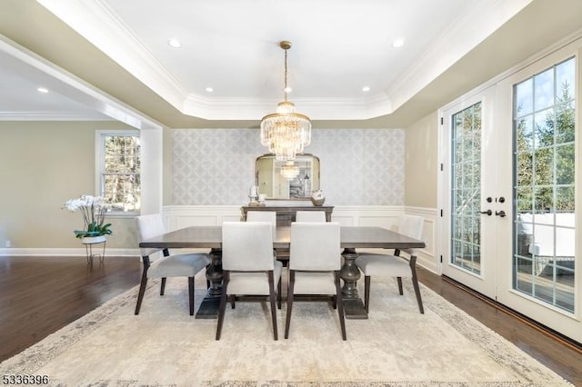 dining space with crown molding, wainscoting, wood finished floors, and wallpapered walls