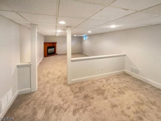 basement featuring a paneled ceiling and carpet floors