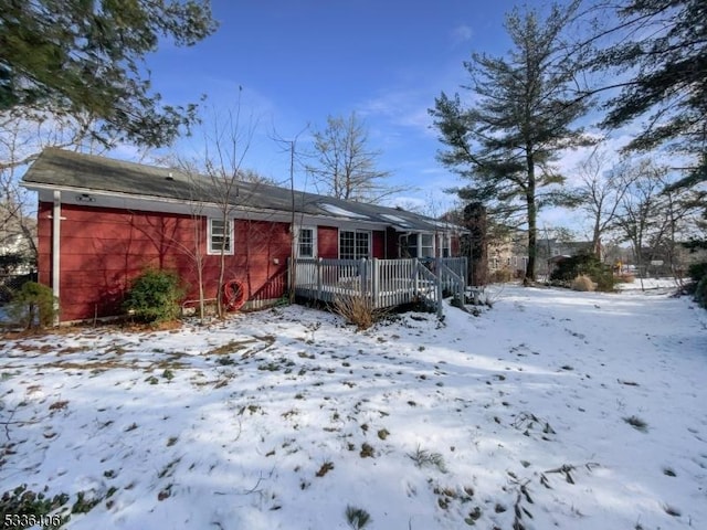 snow covered rear of property with a deck