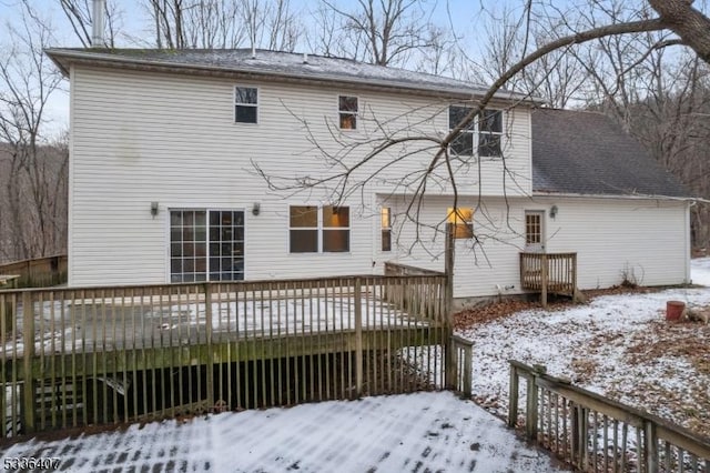 snow covered back of property featuring a wooden deck