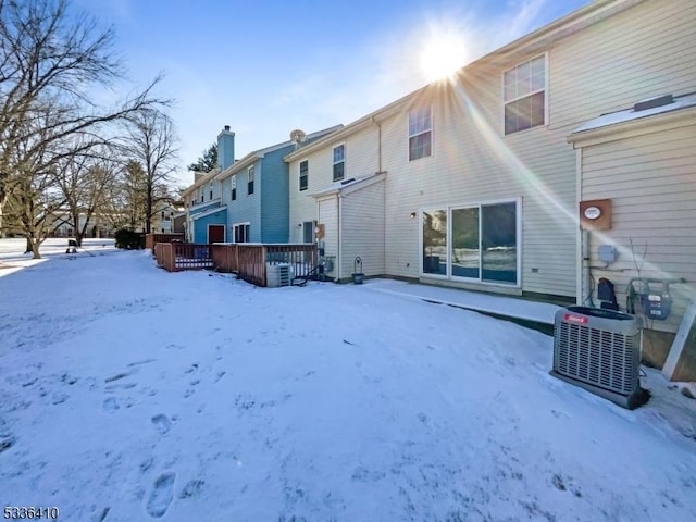 snow covered house featuring central AC unit and a deck