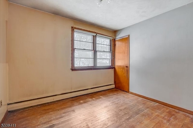 empty room featuring a baseboard radiator and wood-type flooring