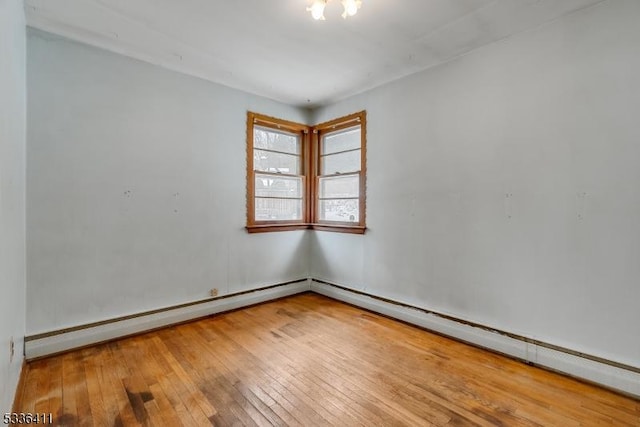 unfurnished room with hardwood / wood-style floors and a baseboard heating unit