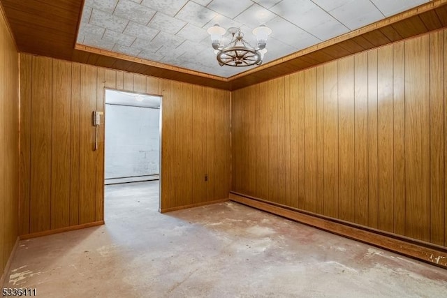 empty room featuring an inviting chandelier, concrete floors, baseboard heating, and wood walls