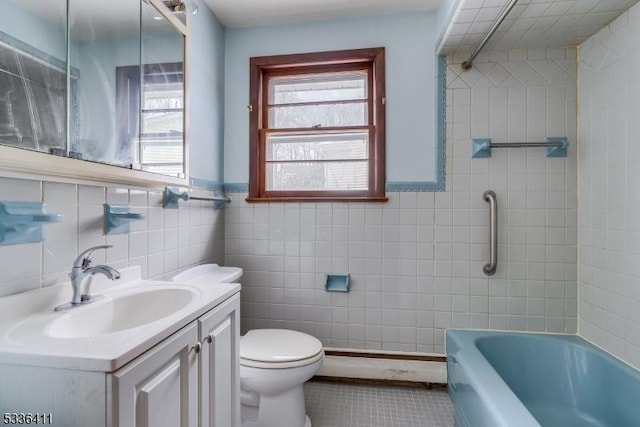 full bathroom with tiled shower / bath, tile walls, vanity, toilet, and tile patterned floors