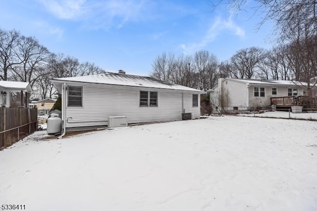 snow covered back of property with a wooden deck