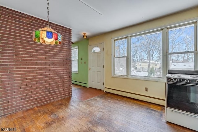 interior space featuring wood-type flooring, brick wall, a baseboard heating unit, and a wealth of natural light