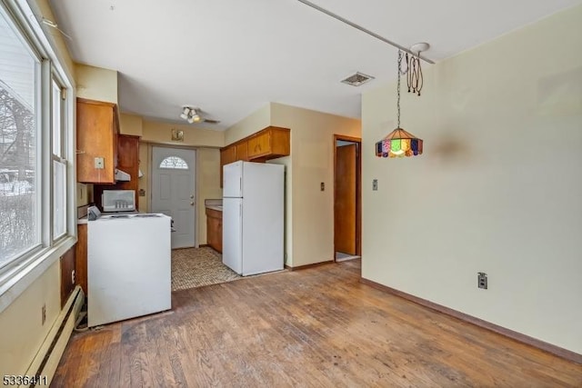 kitchen featuring washer / dryer, decorative light fixtures, light wood-type flooring, white fridge, and a baseboard heating unit