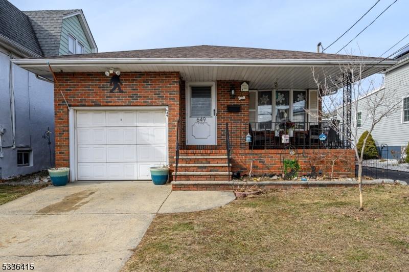 view of front of home with a garage, covered porch, and a front lawn