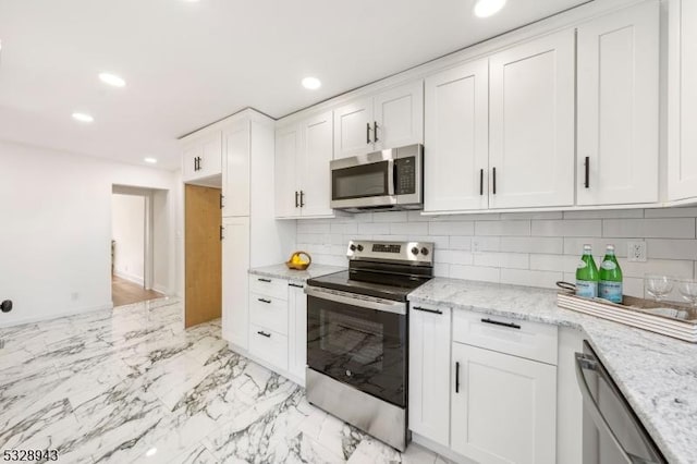 kitchen featuring decorative backsplash, light stone countertops, white cabinets, and appliances with stainless steel finishes