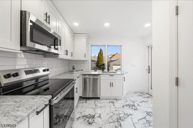 kitchen with white cabinetry, sink, light stone counters, and appliances with stainless steel finishes