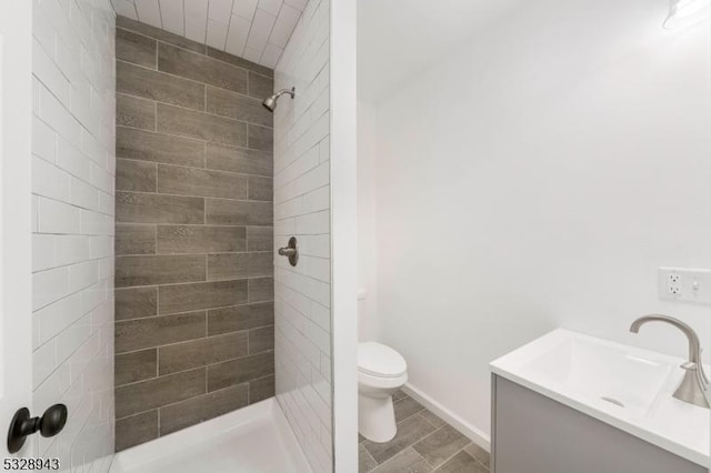 bathroom featuring vanity, a tile shower, and toilet