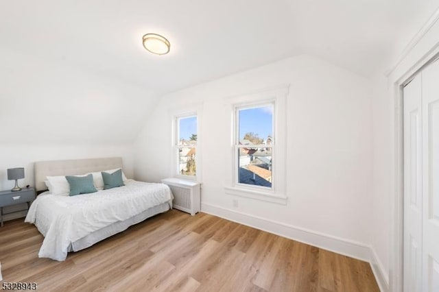 bedroom featuring lofted ceiling and light hardwood / wood-style flooring