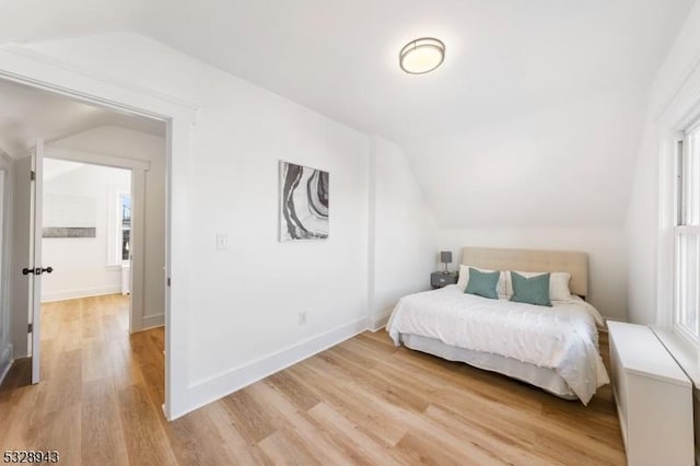 bedroom with lofted ceiling and light wood-type flooring