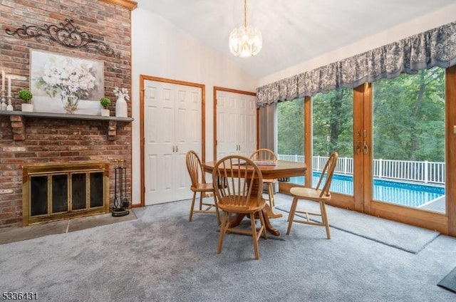 dining area featuring an inviting chandelier, carpet, a fireplace, vaulted ceiling, and french doors