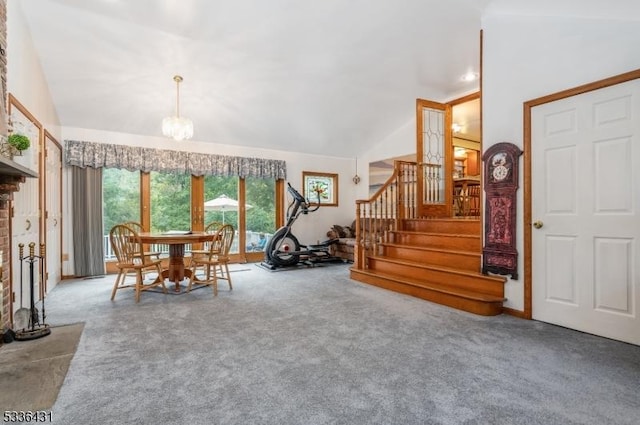 carpeted dining room featuring a notable chandelier, vaulted ceiling, and a brick fireplace