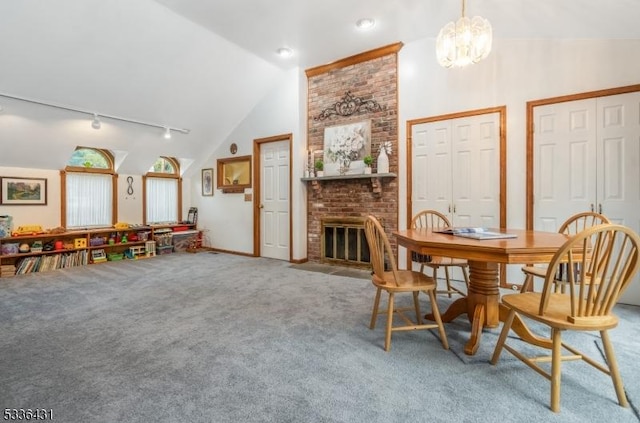 carpeted dining area featuring an inviting chandelier, a fireplace, high vaulted ceiling, and rail lighting