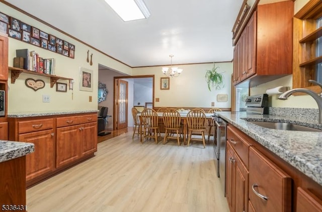 kitchen with pendant lighting, sink, light stone counters, and light hardwood / wood-style flooring