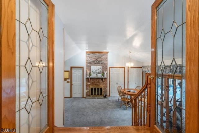 hall featuring an inviting chandelier, lofted ceiling, and carpet floors