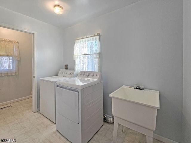 laundry area with separate washer and dryer and sink