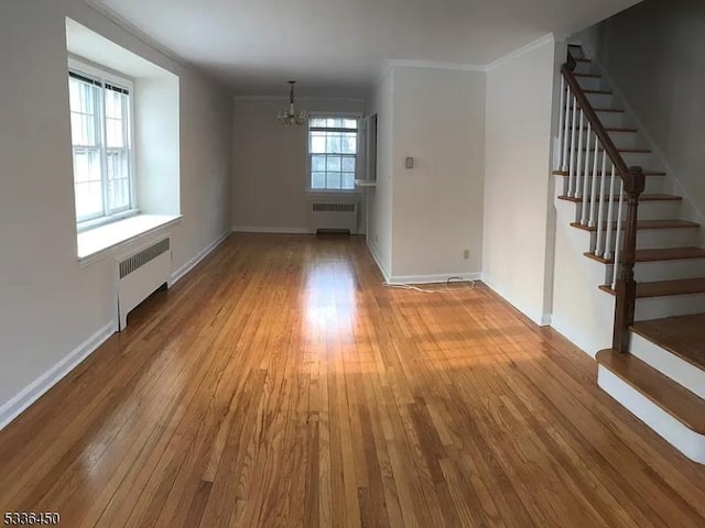 unfurnished room featuring crown molding, radiator, an inviting chandelier, and light hardwood / wood-style flooring