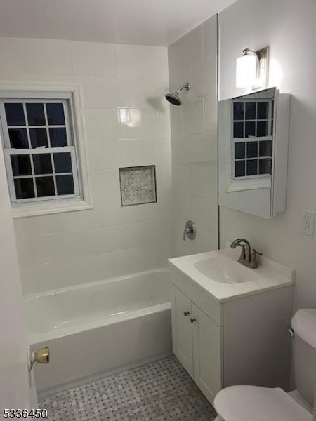 full bathroom featuring vanity, tiled shower / bath combo, and toilet