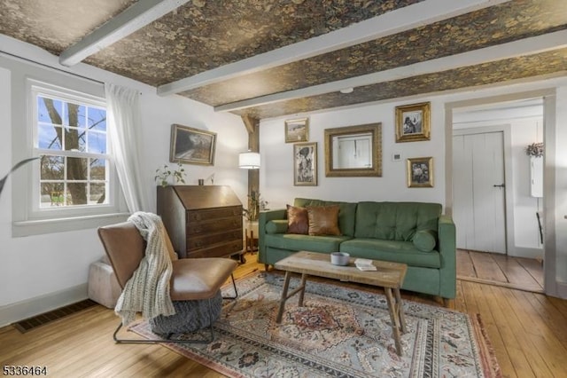 living area featuring beamed ceiling and hardwood / wood-style floors