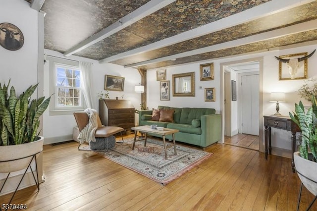 living area featuring beamed ceiling and hardwood / wood-style floors