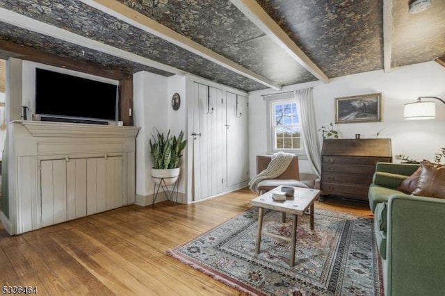 living room featuring beamed ceiling and wood-type flooring