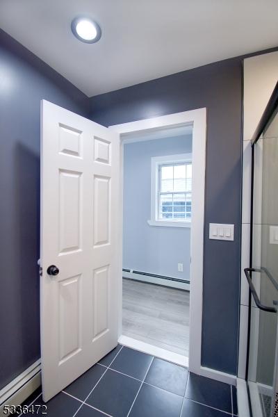 hall featuring dark tile patterned flooring and baseboard heating