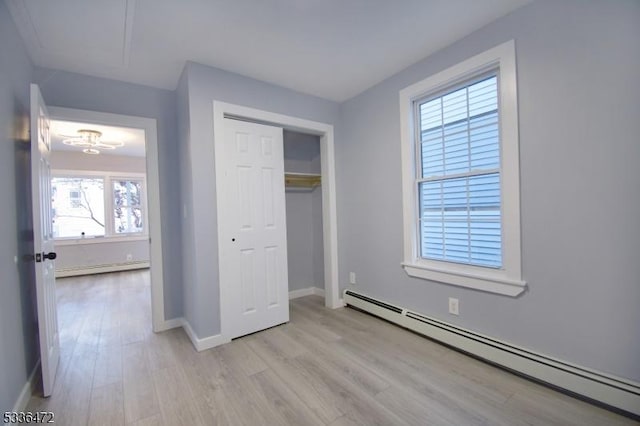 unfurnished bedroom featuring a baseboard radiator, a closet, and light hardwood / wood-style flooring