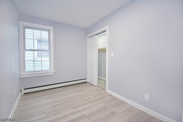 unfurnished room with a baseboard heating unit and light hardwood / wood-style flooring