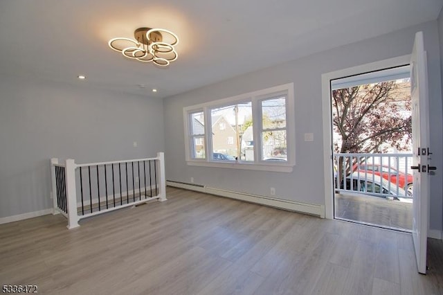 unfurnished room featuring light wood-type flooring and baseboard heating