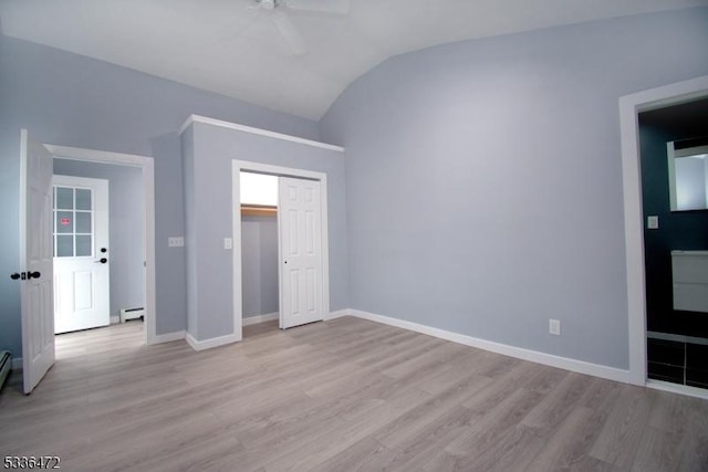 unfurnished bedroom featuring vaulted ceiling, a baseboard heating unit, ceiling fan, light hardwood / wood-style floors, and a closet