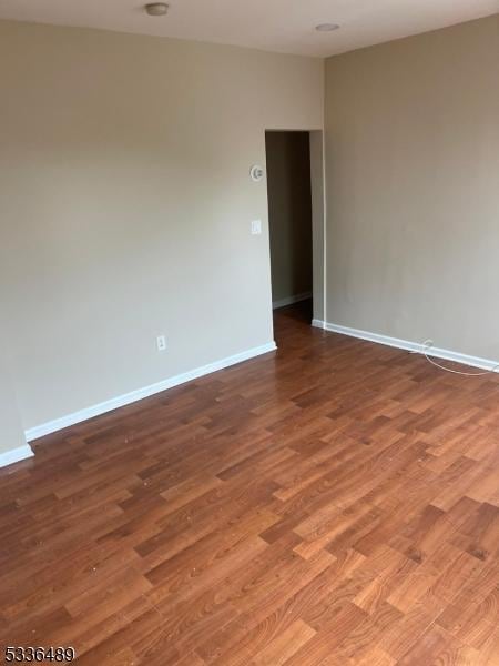 spare room with baseboards and wood finished floors