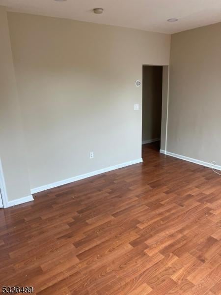 spare room featuring baseboards and wood finished floors